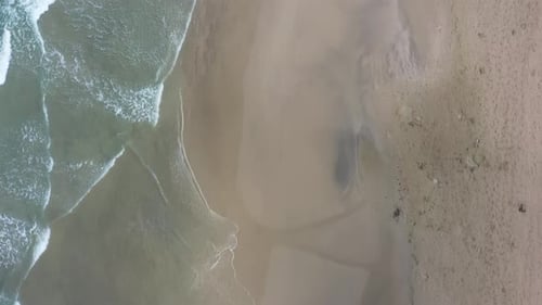 Aerial video along the coastline on a sunny day, waves crashing on the beach, Israel