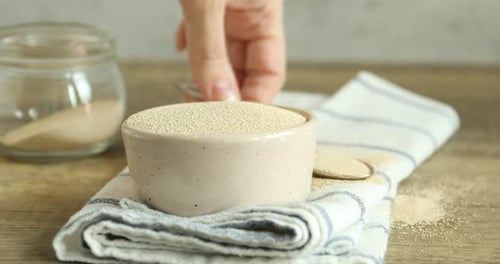 Yeast granules being poured into bowl with spoon