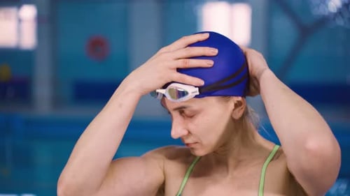 Woman Adjusts Swim Cap Near Indoor Pool