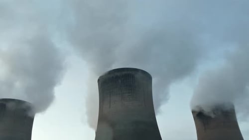 Power plant cooling towers fossil fuel smoke air pollution from below chimney stacks.
