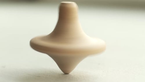 Wooden Toy Top Spinning Smoothly on White Surface
