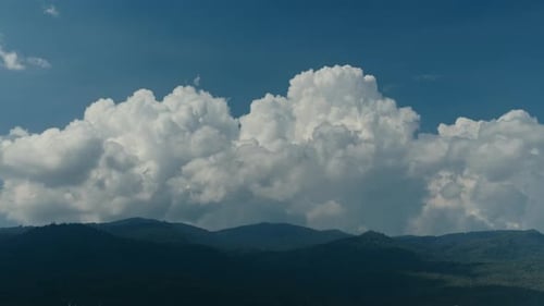 Zeitraffer großer Cumuluswolken, die sich am blauen Himmel über den Hügeln bewegen