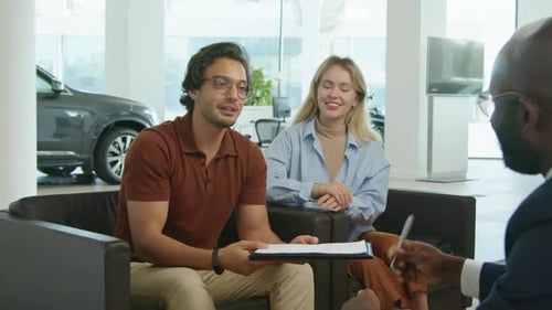 Happy Couple Buying New Car In Dealership Centre