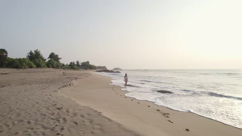 a Beautiful Girl in a Swimsuit Walks Along the Beach at Sunset