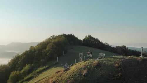 Young couple enjoying the view on the top of the mountains. Hiking in the nature, golden hour sky.