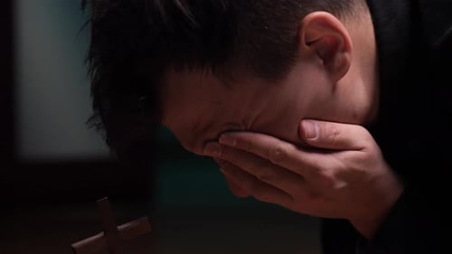 Man Prays With Wooden Cross, Face in Hands