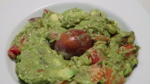 Tilt Down, Bowl of Fresh Guacamole with Avocado Pit, Closeup