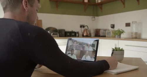 Mann, der von zu Hause aus am Küchentisch arbeitet, Videoanruf, Kollegen über Laptop-Technologie