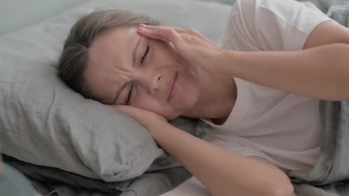 Woman with Headache Lying in Bed, Close Up