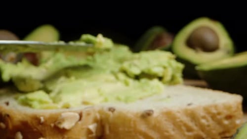 Spread fresh avocado puree on bread for a healthy breakfast. Dolly slider extreme close-up.