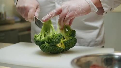 Head Chef Cutting Broccoli with Knife on White Desk in Restaurant Cafe Kitchen Closeup of Broccoli