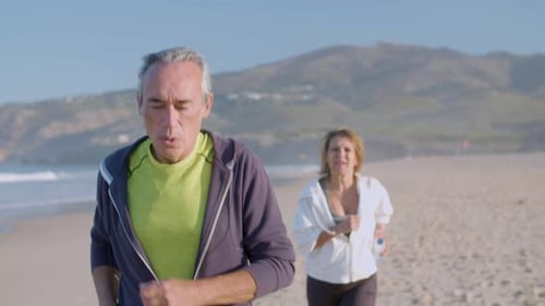 Focused Man and Woman Running Along Ocean Coast on Summer Day