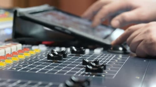Hand adjusts knob on colorful audio console in professional recording studio