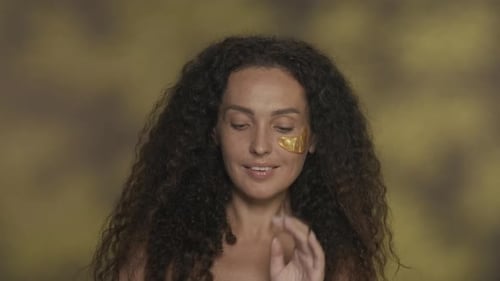 Woman Applies Gold Eye Mask Beauty Treatment