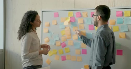 Two Business People Brainstorm Meeting using Adhesive Notes, Working in Office