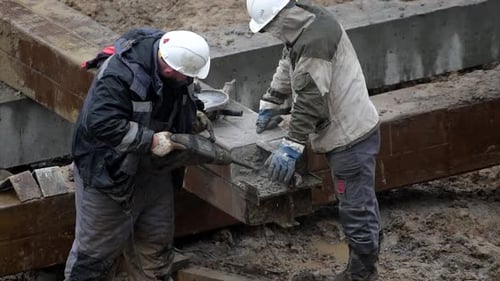 Construction Workers Using Jackhammer on Concrete Beam