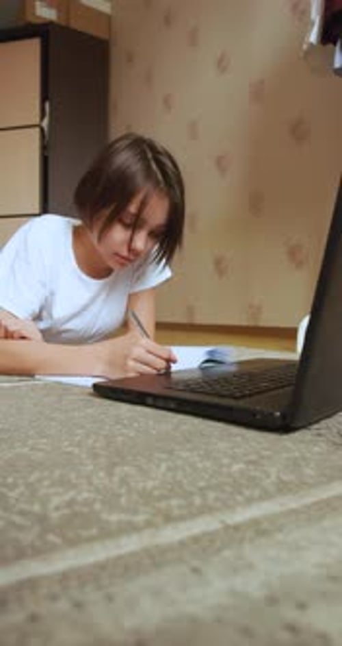 Vertical Footage of a Schoolgirl Doing Homework Online in Front of a Laptop Monitor
