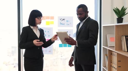 Businesspeople Discussing Graphs and Charts in Office Room