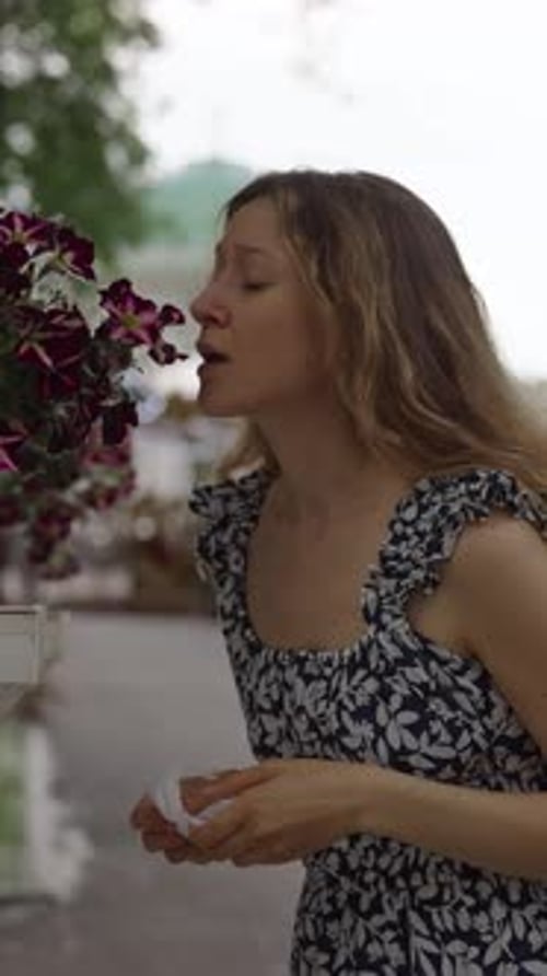 Woman Sniffs Flower in the Park and Sneezes From Seasonal Allergies Wipes Her Nose with Paper Napkin