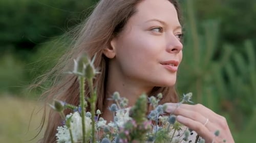Beautiful Young Woman is Holding a Fresh Bouquet of Flowers and Greenery