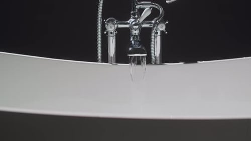 A Woman is Relaxing in a Bathtub with a Candle Glowing in the Background