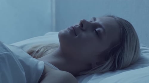 Blonde woman sleeping soundly in bed at night