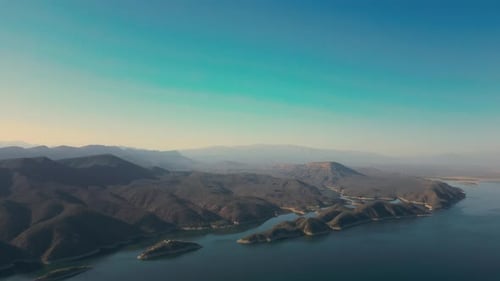 Aerial drone flying over a lake, water dam, with mountains at sunrise. Beautifull dreamy landscape v