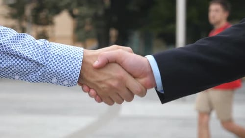 Two Young Confident Businessmen Shaking Hands with Blurred City Background Male Colleagues Greet