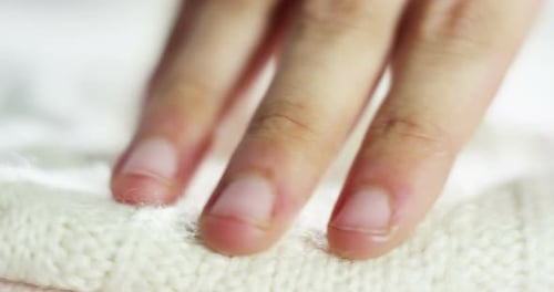 Hand gently touching a soft white knit garment
