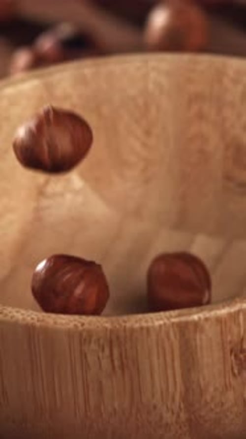 Haselnüsse fallen in eine Holzschale, gefilmt mit einer Hochgeschwindigkeitskamera mit 1000 Bildern pro Sekunde