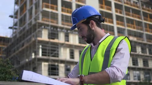 Construction Worker Reviews Plans at Construction Site