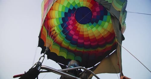 Slow motion close up view of the flame inside of a colorful hot air balloon being inflated before
