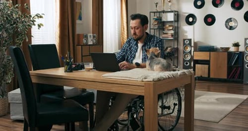Man in Wheelchair Works on Laptop with Dog