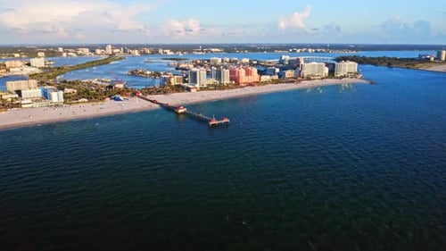 Coastal city skyline with pier extending into blue ocean — aerial perspective