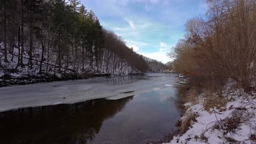 calm river with remaining ice and snow in the woods, day, winter, jib down