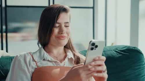 Woman Using Phone While Relaxing on Sofa