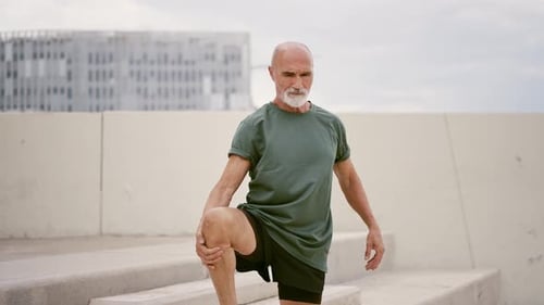 Senior Man Stretching Leg on Urban Concrete Stairs