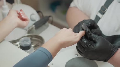 Nail Technician Filing Nails in Bright Salon