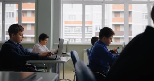 Jugendliche, Schüler, Jungen, die mit Laptops im computergestützten Klassenzimmer einer modernen Schule arbeiten
