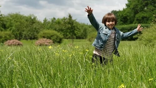 A 5Yearold Boy is Hiding in a Field of Tall Grass Jumping Out and Laughing