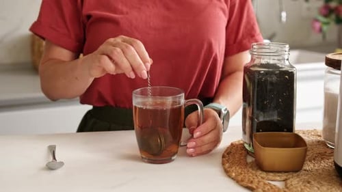 Woman Making Tea at Home with Tea Infuser