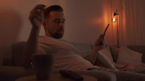 Man Using Tablet and Drinking Coffee at Home