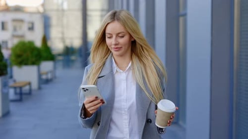 Woman Walks With Mobile Phone and Coffee