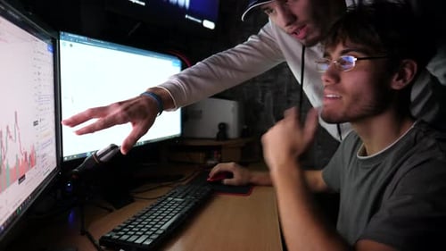Young Adults Analyzing Computer Screens in Dark Office