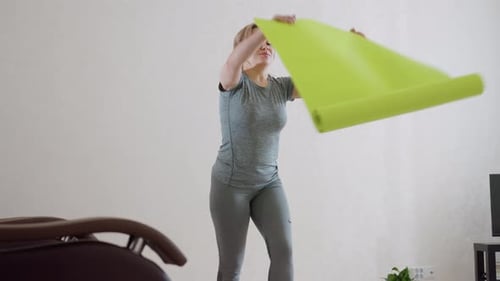 Woman Prepares To Unroll Bright Green Fitness Mat In Minimalist Home