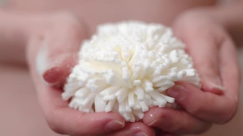 Woman holding foamy loofah in hands, close up