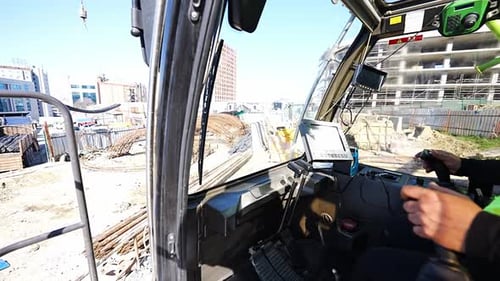 Un grutier sur le site de construction commande au camion de déplacer les barres d'armature vers une autre zone