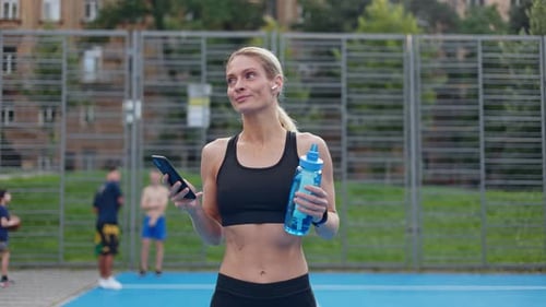 Cheerful Sporty Lady Using Gadgets While Working Out on Street Stadium
