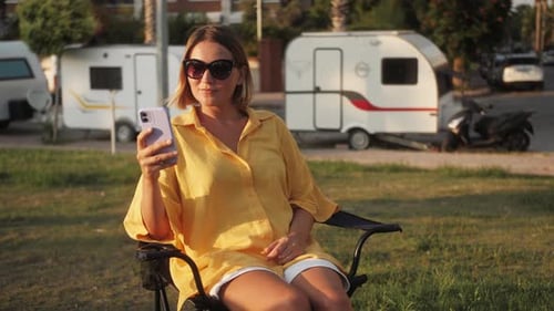 Woman Relaxing with Smartphone at Campsite