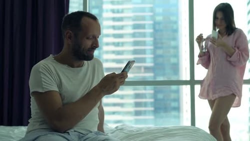 Un jeune couple navigue sur le Web sur des smartphones dans une chambre accro